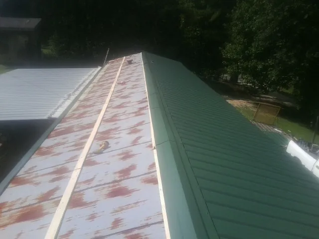 Old rusted panels beside newly installed green metal roofing — Wind Damage Roof Repair by Roofing Brothers in Hazelton
