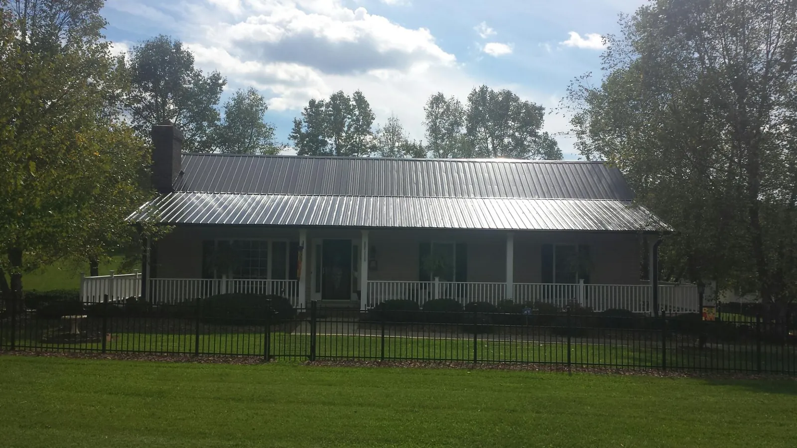 Gray metal roof on a brick ranch with a full width front porch — Gutter Guard Installation work by our crew in Hazelton