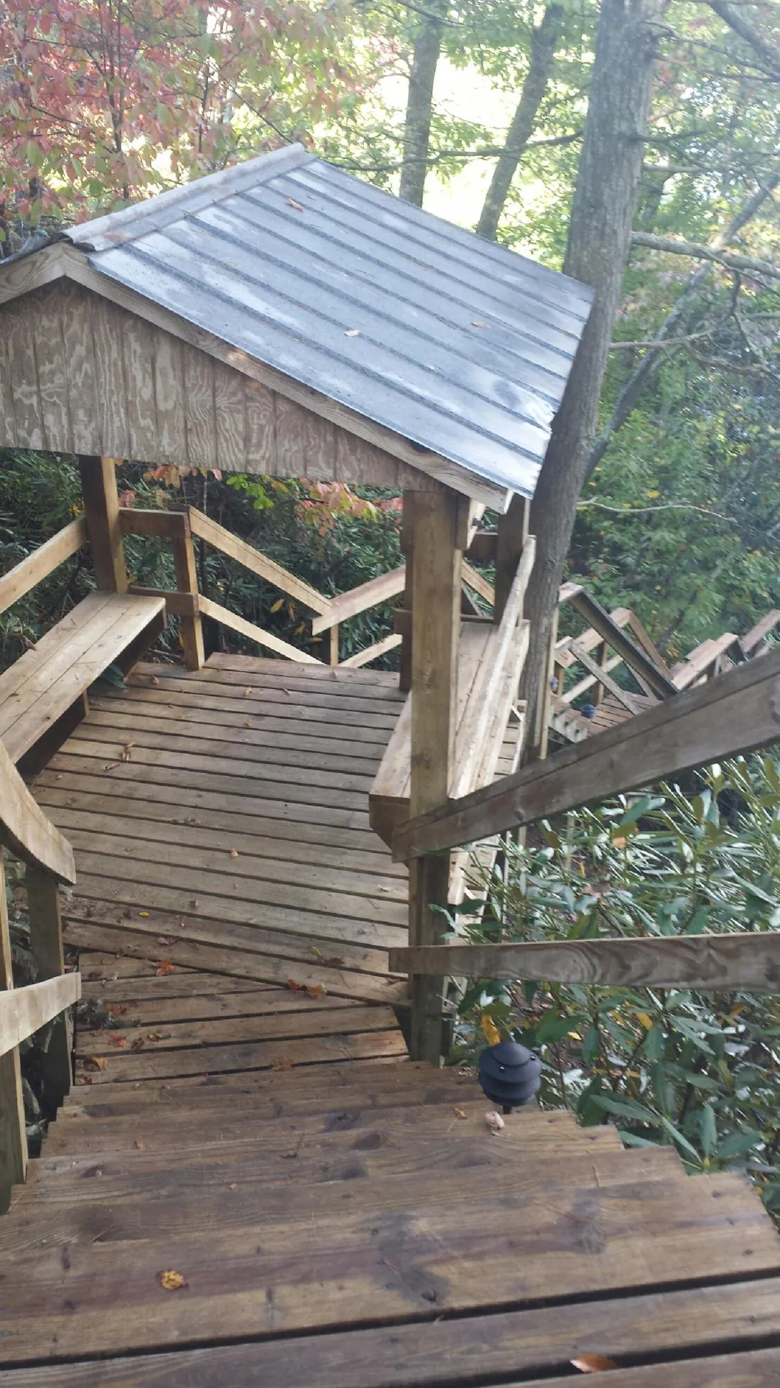 Metal roofed shelter over wooden steps on a wooded walkway — Skylight Repair & Installation work by our crew in Hazelton