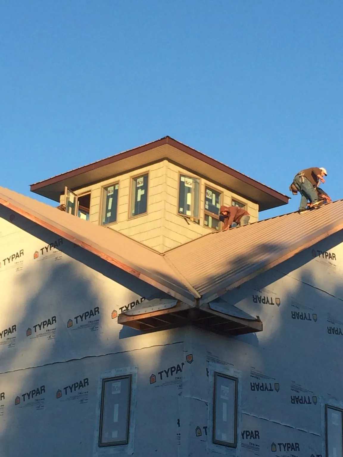 Roofers working around a rooftop cupola on a new metal roof at sunset — Roof Waterproofing in Hazelton by Roofing Brothers